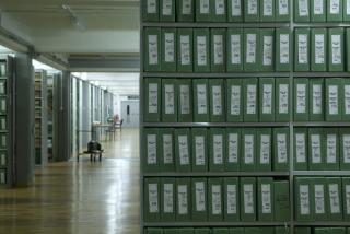 Bralne mize ob polnih policah fasciklov z arhivskim gradivom